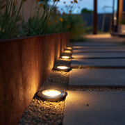 Row of solar-powered garden lights along a pathway with potted plants.